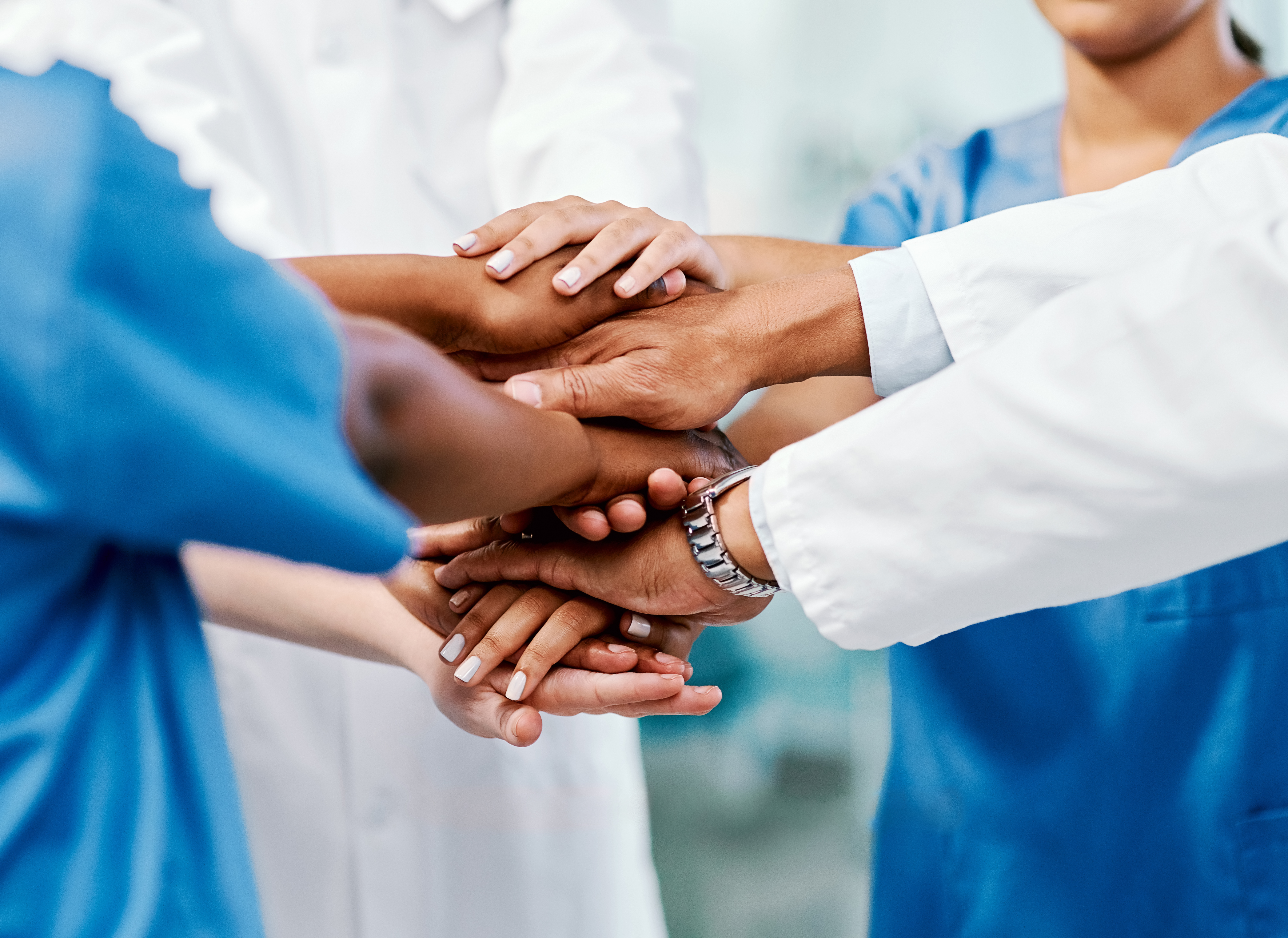 Healthcare professionals unite their hands in a show of teamwork and commitment to patient care.