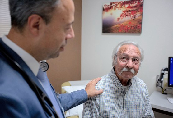 An oncologist touching the shoulder of an older male patient