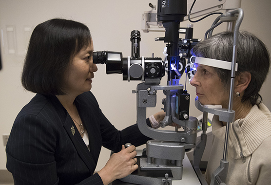 Eye doctor performing an eye exam for AMD on older patient.