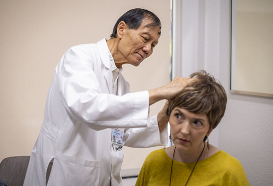 A dermatologist examines a woman's scalp.