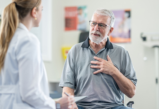 Older man talking to a health care provider in a clinic.