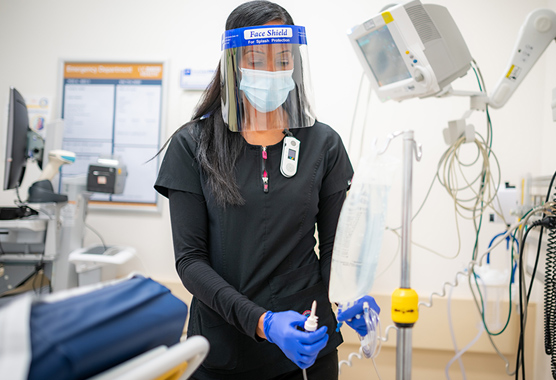Female nurse in scrubs, a mask and a face shield in the hospital