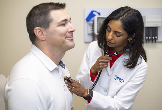 Female physician listening to male patient’s heart with a stethoscope