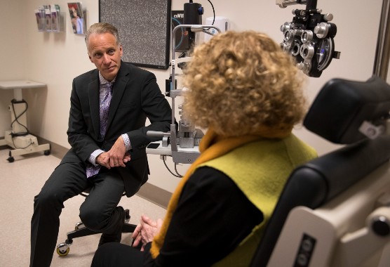 Male eye doctor speaking with a female patient in an eye exam room