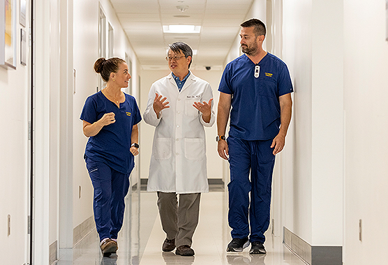 Three health care providers talking while walking down a clinic hallway
