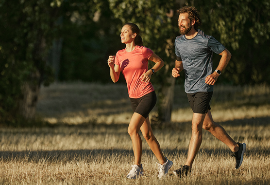Man and woman running in a field.