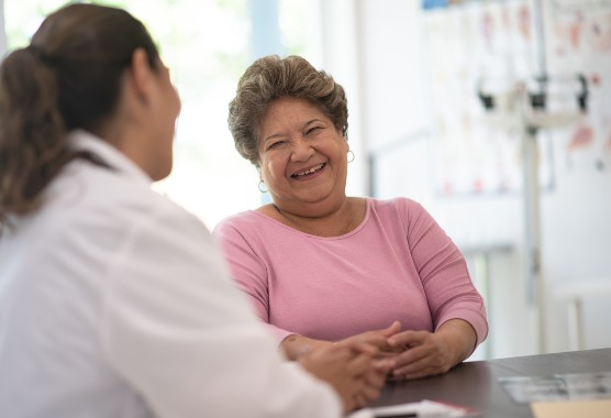 Mature woman in a pink sweater smiling at her health care provider