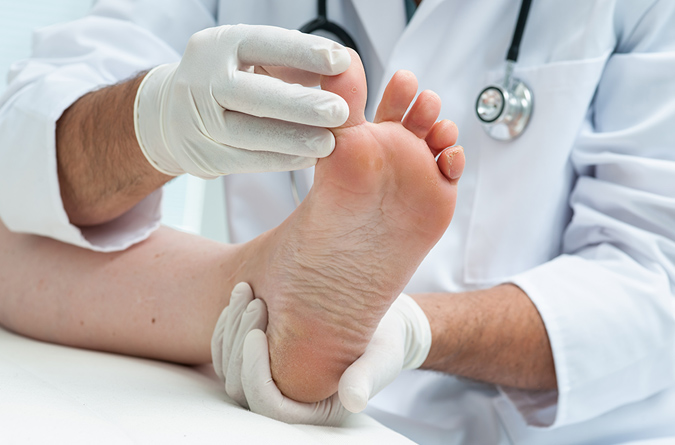Health care provider examining a patient’s foot between the toes.