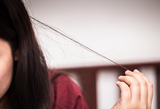 Close up of a woman holding a strand of her hair.
