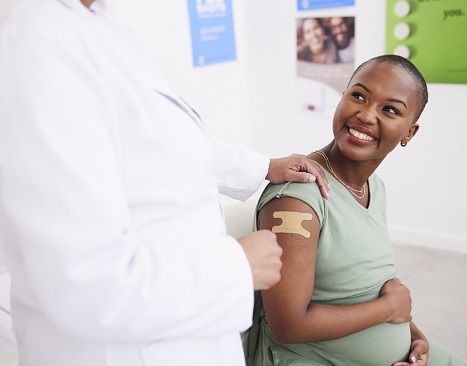 Pregnancy woman smiling after getting immunization in her arm