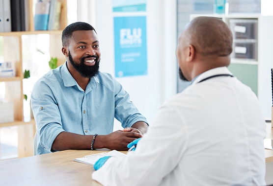 Male patient smiling while talking to male health care provider