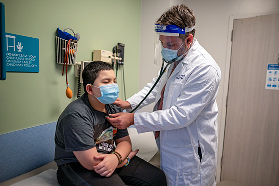 Young boy with male health care provider listening to his heart with a stethoscope