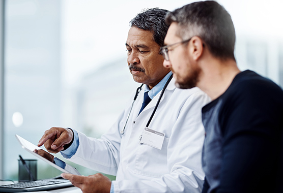 Urologist talking to male patient with Peyronie’s disease.