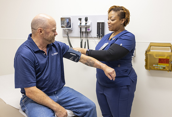 A man getting his blood pressure taken by a medical provider in a clinic.