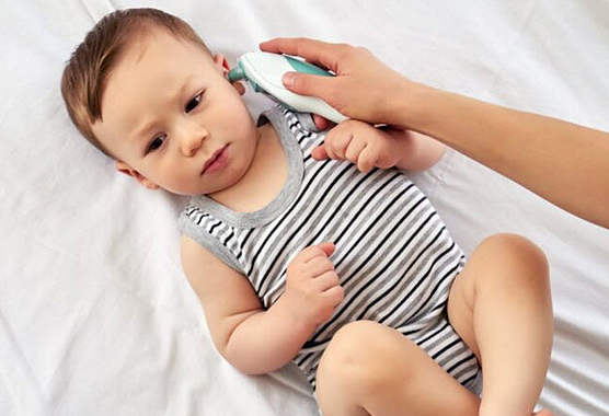 Baby having his temperature taken with an ear thermometer.