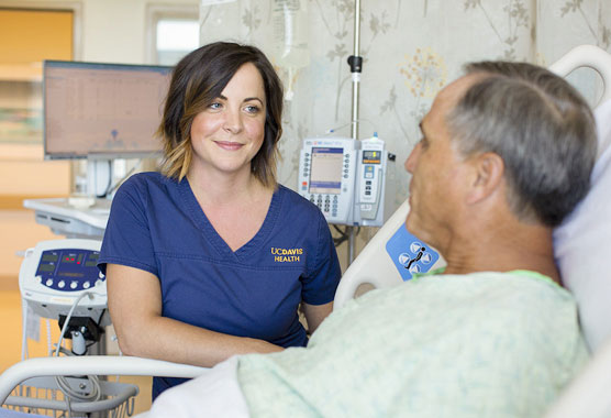 Female nurse smiling at a male patient in a hospital bed
