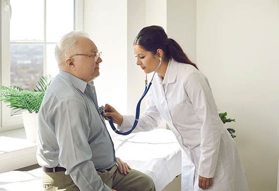 Female health care provider listening to male patient’s heart with stethoscope