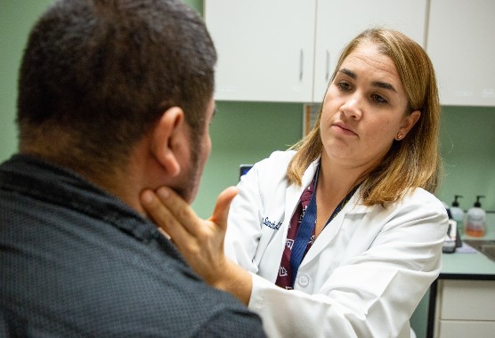 Female provider examining a male patient's thyroid gland