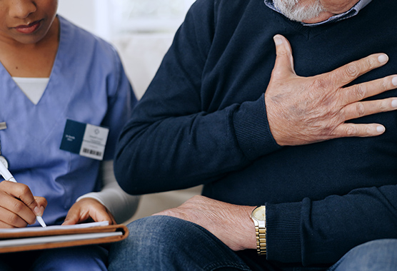 Man with his hand on his chest talking to female provider about his tuberculosis symptoms.