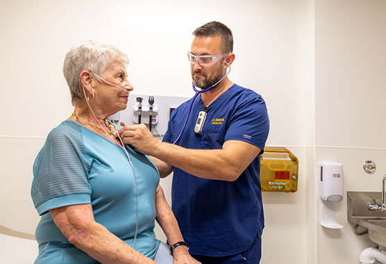 Male nurse listening to older woman’s heart with a stethoscope