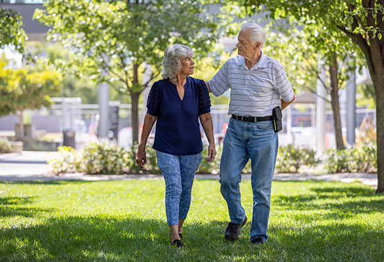 Two mature adults walking outside and looking at each other