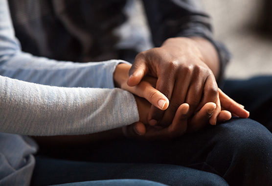 Male and female hands clasped together.