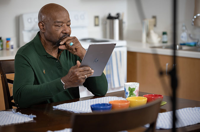 Man sitting at a table looking at a mobile tablet