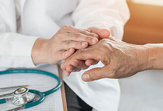 Medical provider’s hands holding onto an older person’s hand