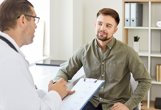 Patient sitting and talking to his specialist about digestive disorders in clinic.