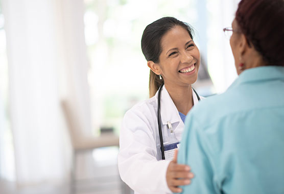 Female health care provider smiling with her hand on a patient's shoulder