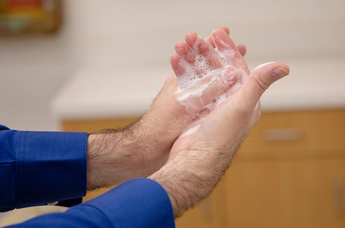 A man’s hands as he washes them with soap and water.