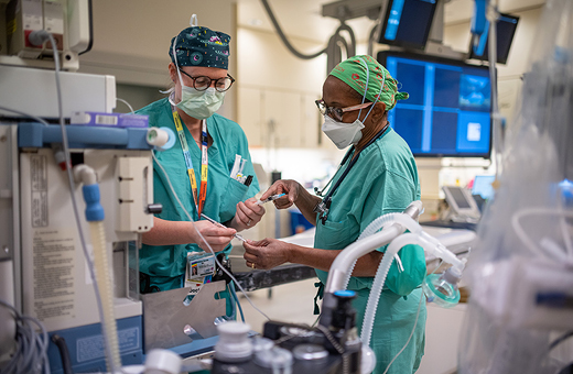 Two anesthesiologists preparing for an IV injection in the operating room