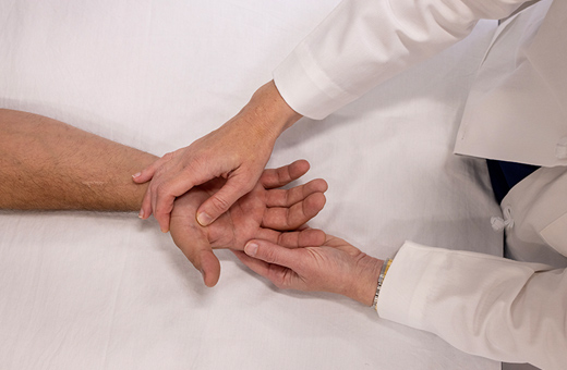 Hand surgeon examining patient’s hand on table after surgery.