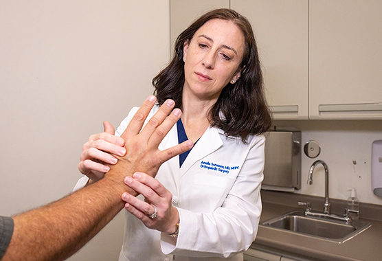 Hand surgeon examining patient’s hand in clinic.