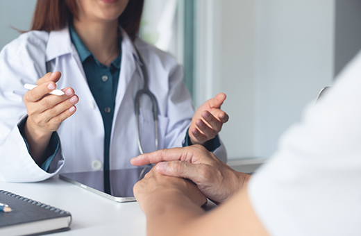A doctor speaks to a patient at a desk.