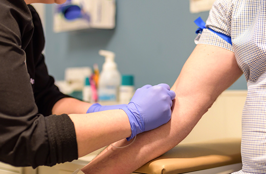 Health care provider preparing to draw blood from patient’s arm