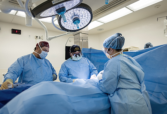 Three medical professionals performing surgery.