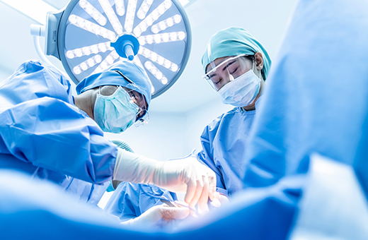 Surgeons performing hip replacement on patient in operation room.
