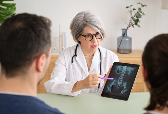 Physician sharing a hip x-ray with a patient and their loved one.