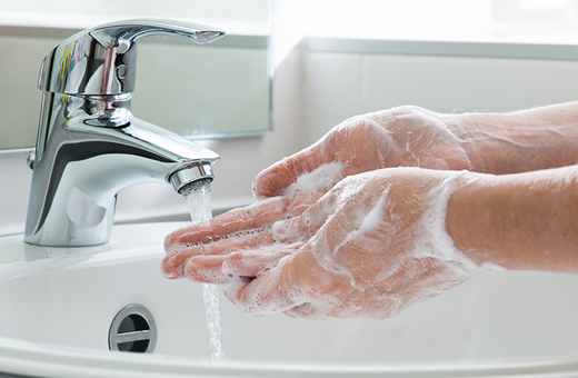 A person washing their hands with soap in a sink.
