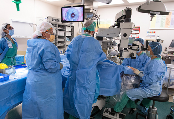 Surgeon and health care providers working on patient’s eye in surgery room.