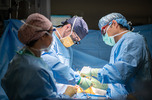 A team of 3 surgeons performing transplant surgery in the operating room.