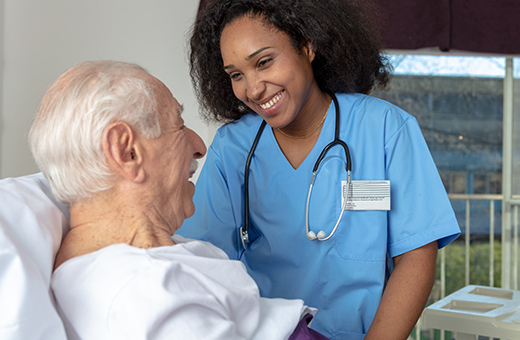 Female health care provider talking to male patient in hospital bed after minimally invasive surgery.