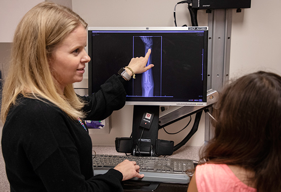 Female health care provider showing x-ray image to patient.