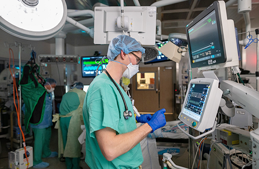 Male anesthesiologist monitoring screens during surgery.