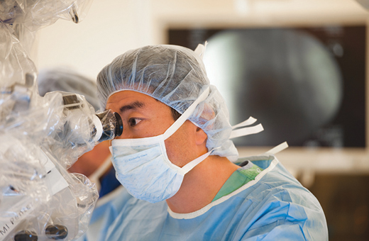 Male surgeon in the OR looking through a microscope