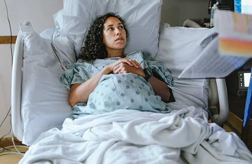Pregnant woman laying in hospital bed listening to health care provider before delivery.