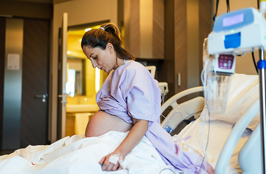 Pregnant woman sitting up in hospital bed preparing for child birth.