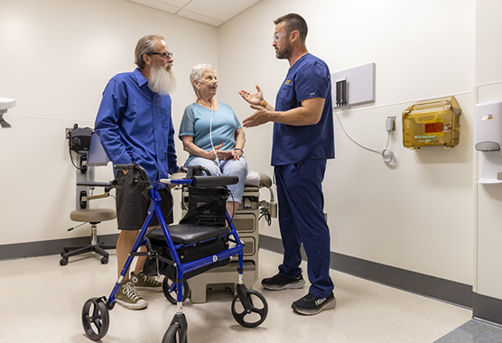 An occupational therapist speaks with a woman using a walker and her partner.