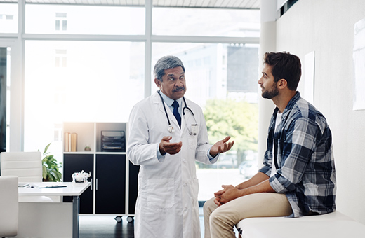 A man dressed in comfortable clothing speaks with a doctor.
